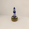Blue and white striped lighthouse model, wooden base, nautical theme decoration, including rudder, shell and fishing net details Picture